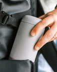 Man putting grey Carter Move Mug in bag.