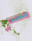 Happy Matcha Stick ripped open and surrounded by matcha powder