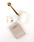 Gold coffee scoop, coffee caramels, cream mug and box of coffee on white background