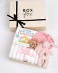 BOXFOX creme gift box next to open box containing a book, swaddle, teether, baby beanie and bunny rattle.