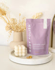 Lavender Body Polish bag on marble tray next to candle and rings