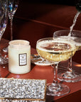 Sparkling Cuvée Medium Glass Jar Candle next to champagne coupes and sparky things