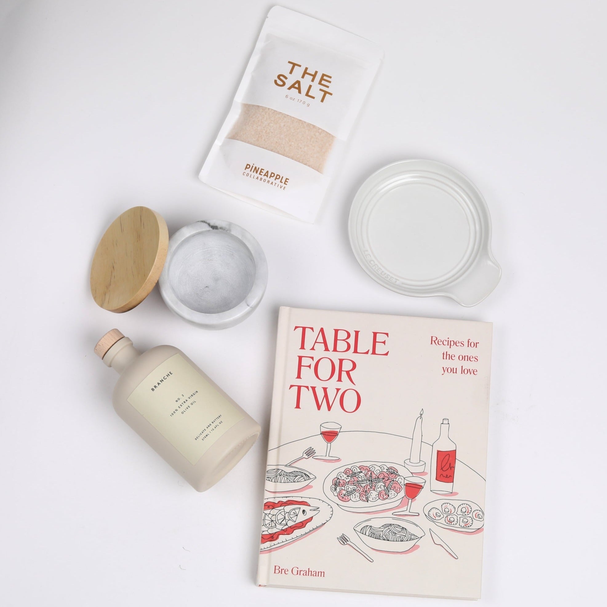 Table for Two ready to ship products including &quot;Table for Two&quot; cookbook, Le Creuset spoon rest, Branche olive oil, The Salt, and marble salt cellar