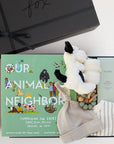 BOXFOX black New Family Gift Box packed with PEHR cozy grey kimono onesie 3-6 months, Jellycat puppy lovey, Our Animal Neighbors book, Pipette baby oil, Alva sage green teether, and Alva grey beanie