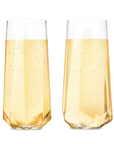 Two clear, stemless champagne flutes filled with bubbly champagne photographed on white background