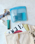 Blue Stasher bag filled with essentials and surrounded by girly things.