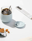 Mint Glass Cup with drink, ice and straw in it, next to granola bar and straw set.