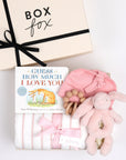 BOXFOX creme gift box next to open box containing a book, swaddle, teether, baby beanie and bunny rattle.