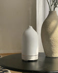 White Stone Essential Oil Diffuser on table next to vase
