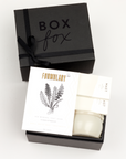 BOXFOX Black Gift Box filled with Voluspa Coconut Papaya Tin Candle, Formulary 55 Eucalyptus + Peppermint Foot Soak and Mast Brothers 2 Mini Tea Chocolate Bars