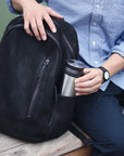 Man putting Stainless Steel travel tumbler in backpack.