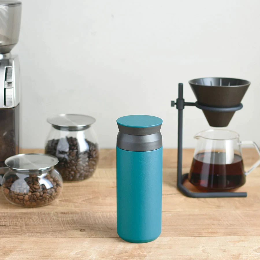 Turquoise Travel Tumbler on table next to coffee beans and coffee pot.