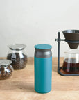 Turquoise Travel Tumbler on table next to coffee beans and coffee pot.