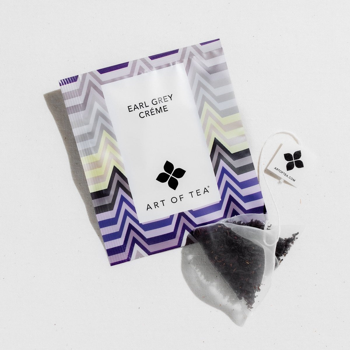 Packet with grey, cream, and purple triangular lines, with tea sachet off to the side.