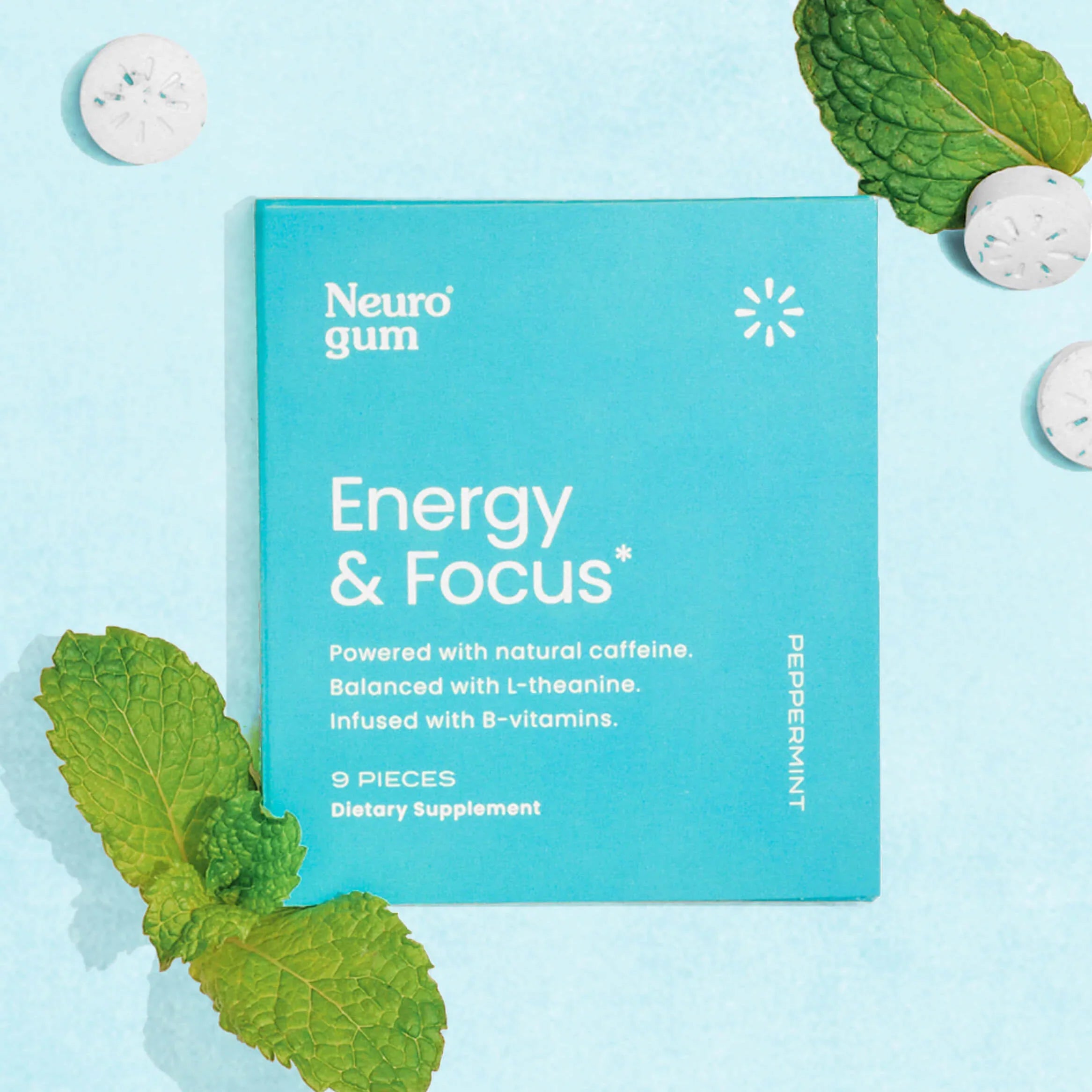 Energy &amp; Focus Gum on blue background surrounded by gum tablets and mint leaves.