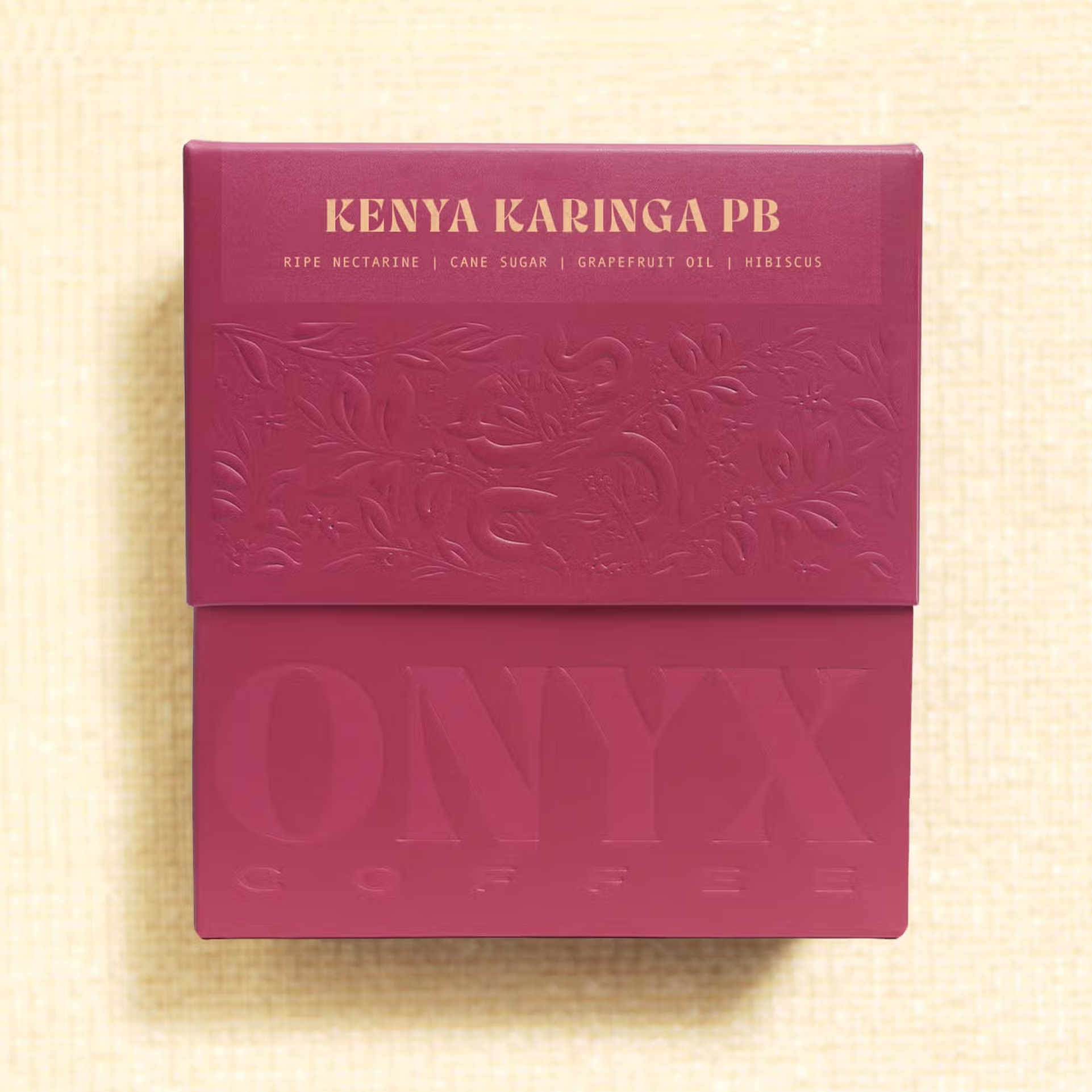 Magenta box packaging with embossed ONYX on the bottom half. Top half has embossed vines with Yellow text at the top with the coffee name and notes