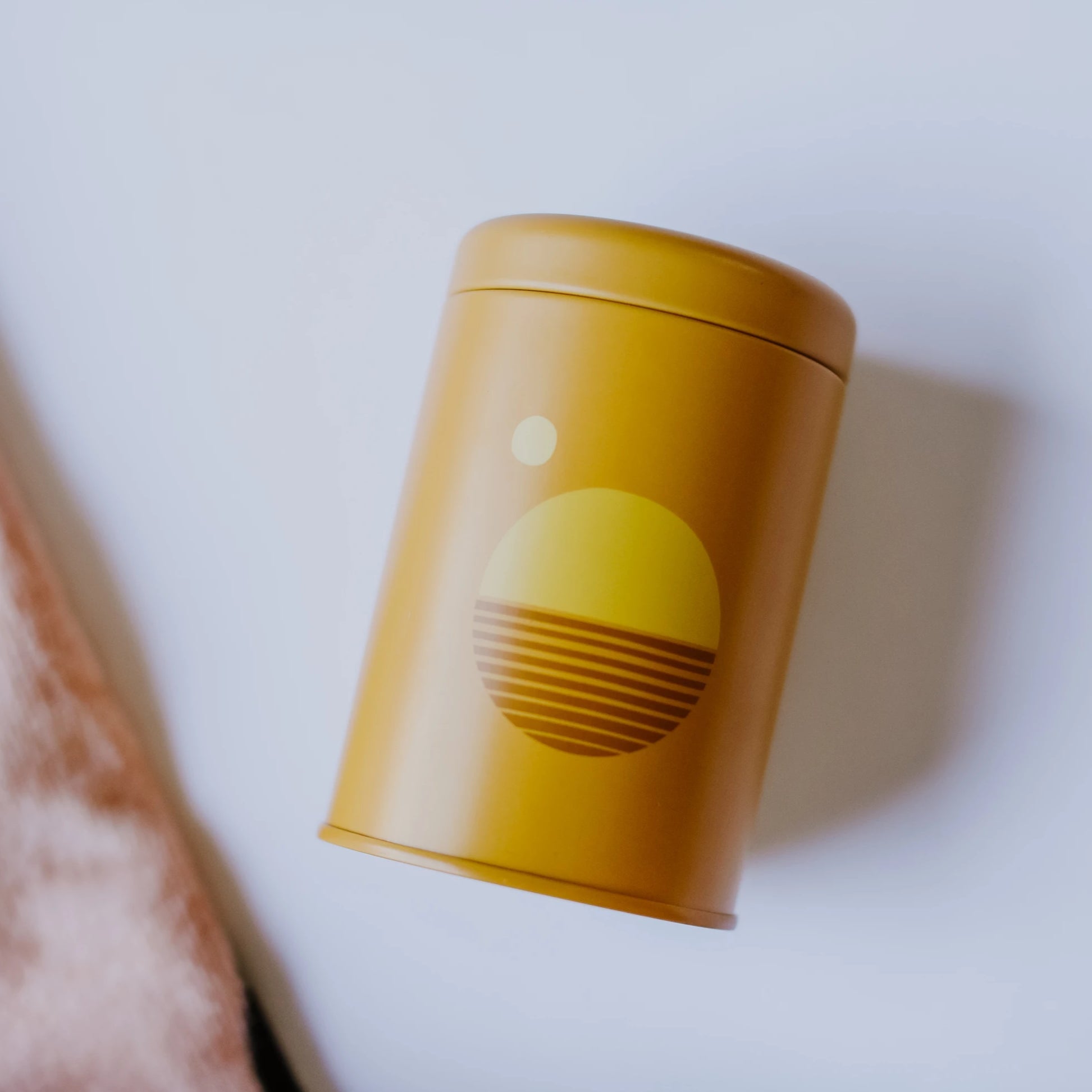 Dark yellow cylinder container with yellow and orange sun.