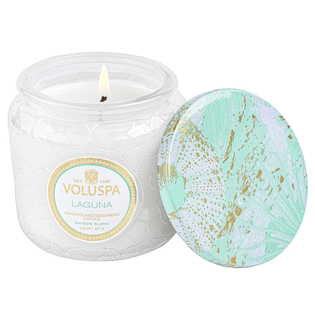 Laguna scented candle with teal lid and accents on the label. lid is off leaning against the lit candle
