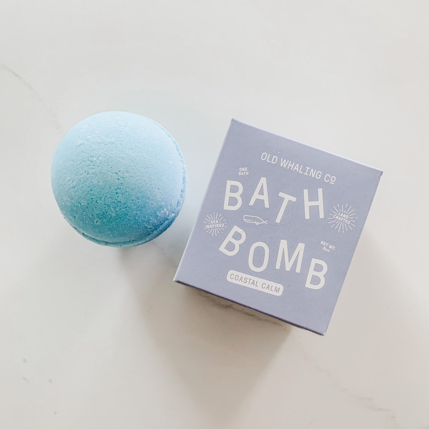 Blue bath bomb next to blue box with white text.