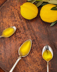 Arbosana Extra Virgin Olive Oil in spoons on cutting board, next to olive branch and lemons