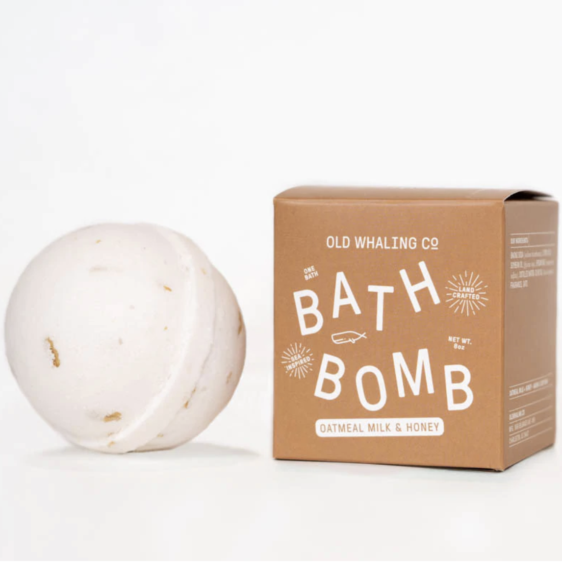 White round bath bomb next to a brown box with white writing.
