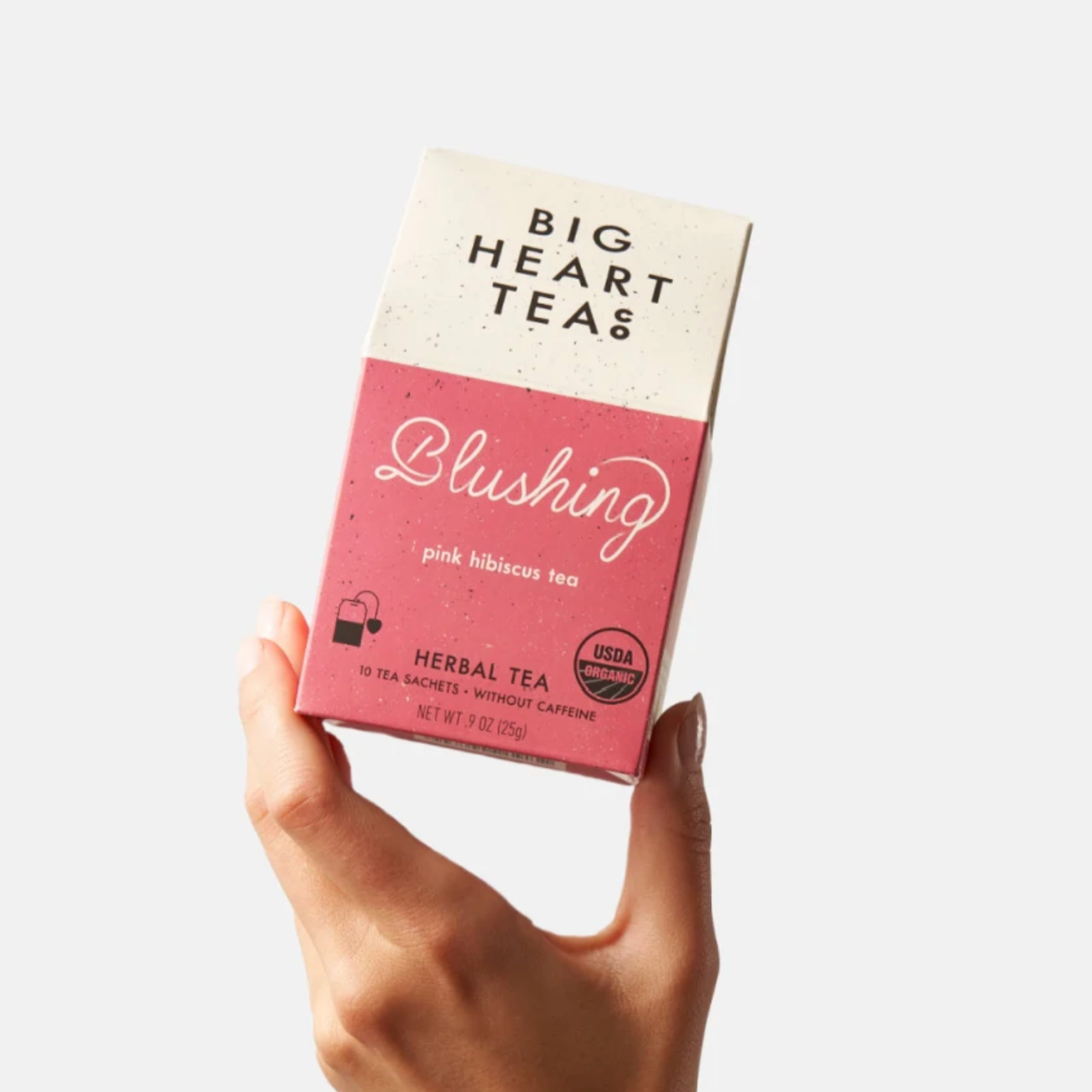 Hand holding box of pink blushing tea in the air