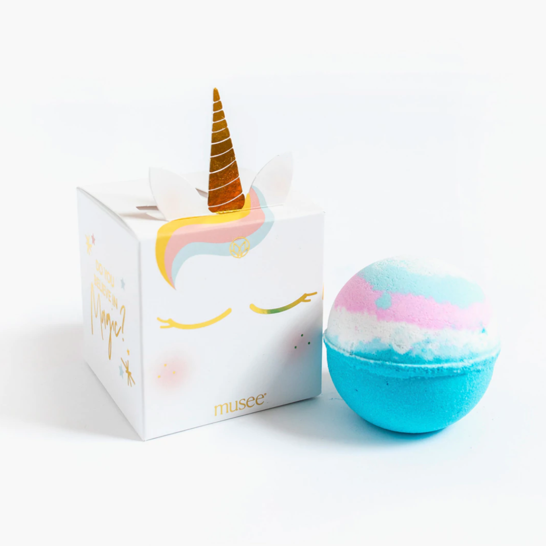 Image shows the packing of the Unicorn Bath Bomb to the left, at a slight slant with the side showing which reads "Do you believe in magic?" and the blue, pink and white bath bomb to the right.