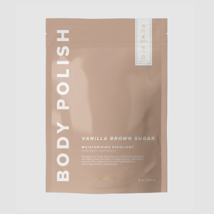 Rectangular, sealed, mauve package with white lettering that reads "BODY POLISH" on side and "VANILLA BROWN SUGAR MOISTURIZING EXFOLIANT" on bottom right. Photographed on grey background. 