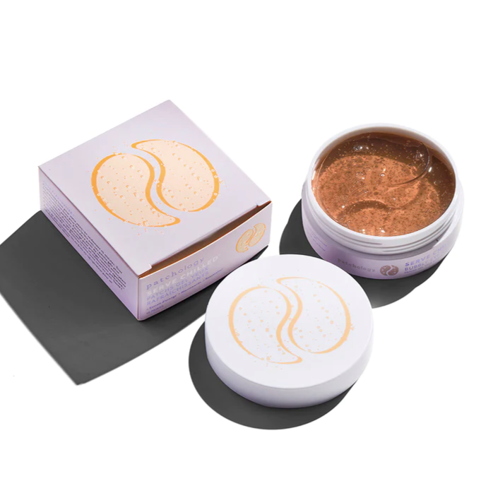 A light purple square box with light orange bubbly eye patch graphic on top. To the left is an open plastic jar of Bubbly Brightening under eye pads with light purple lid below. Photographed on white background.