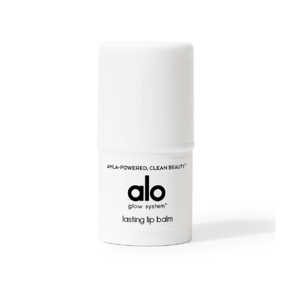 A small, white, cylindrical, plastic container with black text that reads, " Amla-powered, clean beauty alo glow systems lasting lip balm". Photographed on white background.
