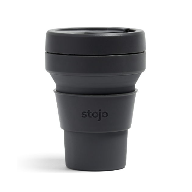 A black plastic travel mug with silicone sleeve that reads, &quot;stojo&quot; photographed on white background. 