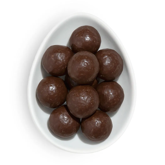 Several balls of chocolate covered peanut butter cookie dough resting in a white, egg shaped porcelain dish photographed on white background.