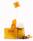 Image shows the SAYSO Old Fashioned Ready-to-make cocktail sachet in the forefront of the image, with an Old Fashioned made cocktail towards the back. There is an unpackaged sachet in the drink, as well as some of the ingredients surrounding it.