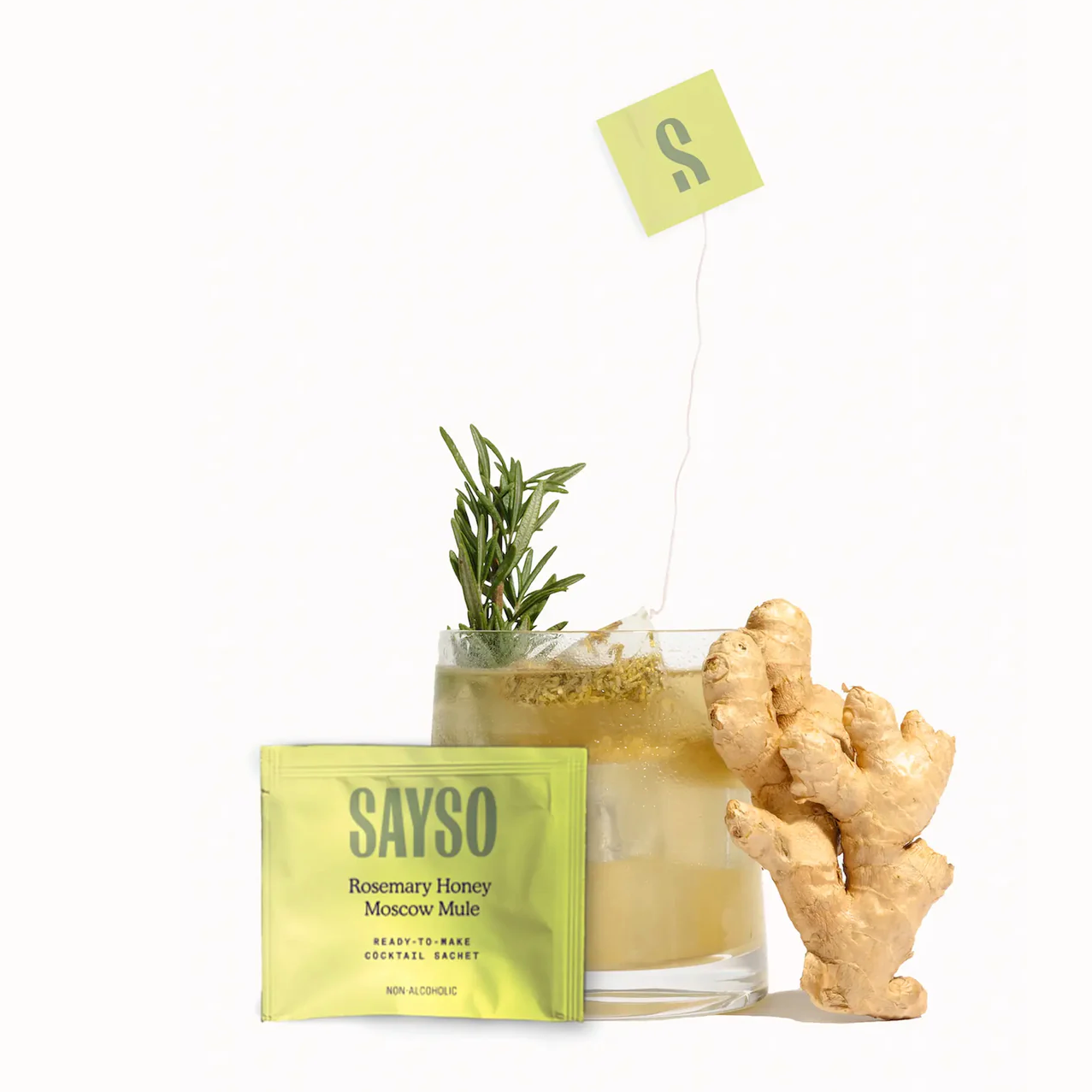 Image of the SAYSO Rosemary Honey Moscow Mule sachet, a moscow mule cocktail with the sachet soaking, and ginger root to the right.