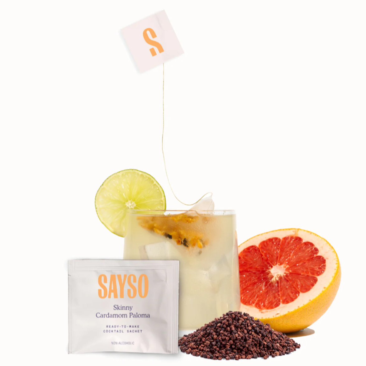 SAYSO Skinny Cardamom Paloma sachet with a Paloma cocktail in the background and a grapefruit to the right.