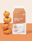 Pumpkin Spice Oat Milk Calming Plant-Based Milk Mask on orange and white background next to stack of mini pumpkins.