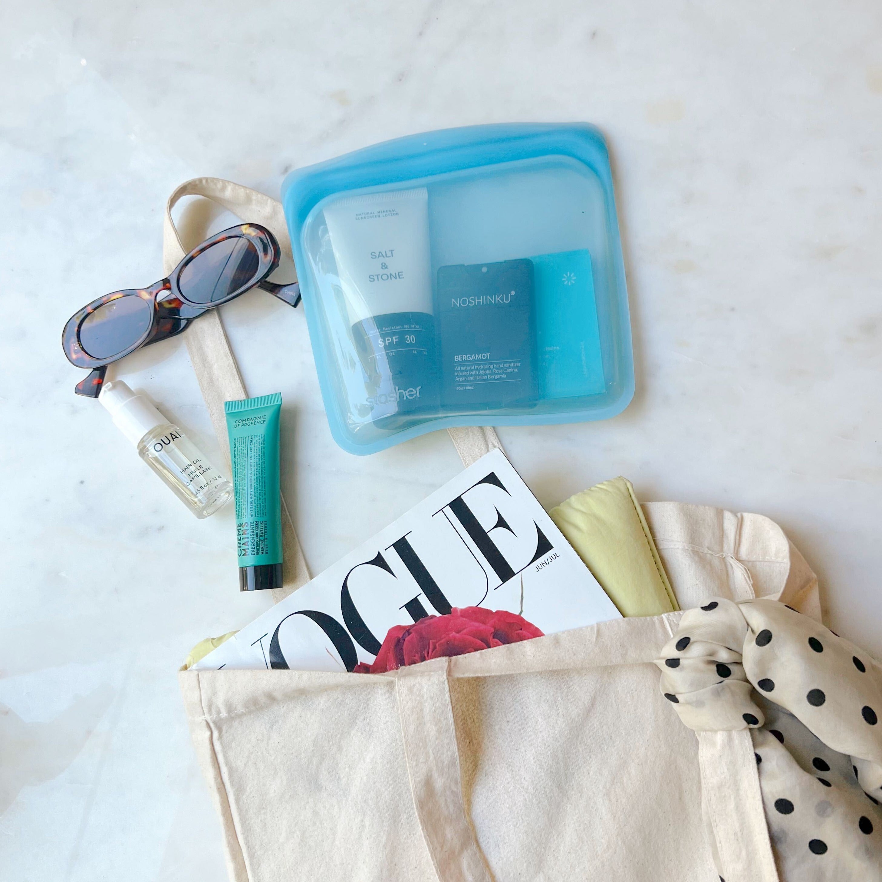 Blue Stasher bag filled with essentials and surrounded by girly things.