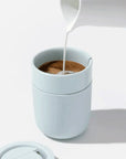 Milk pouring into Mint Ceramic Porter Mug on white background.