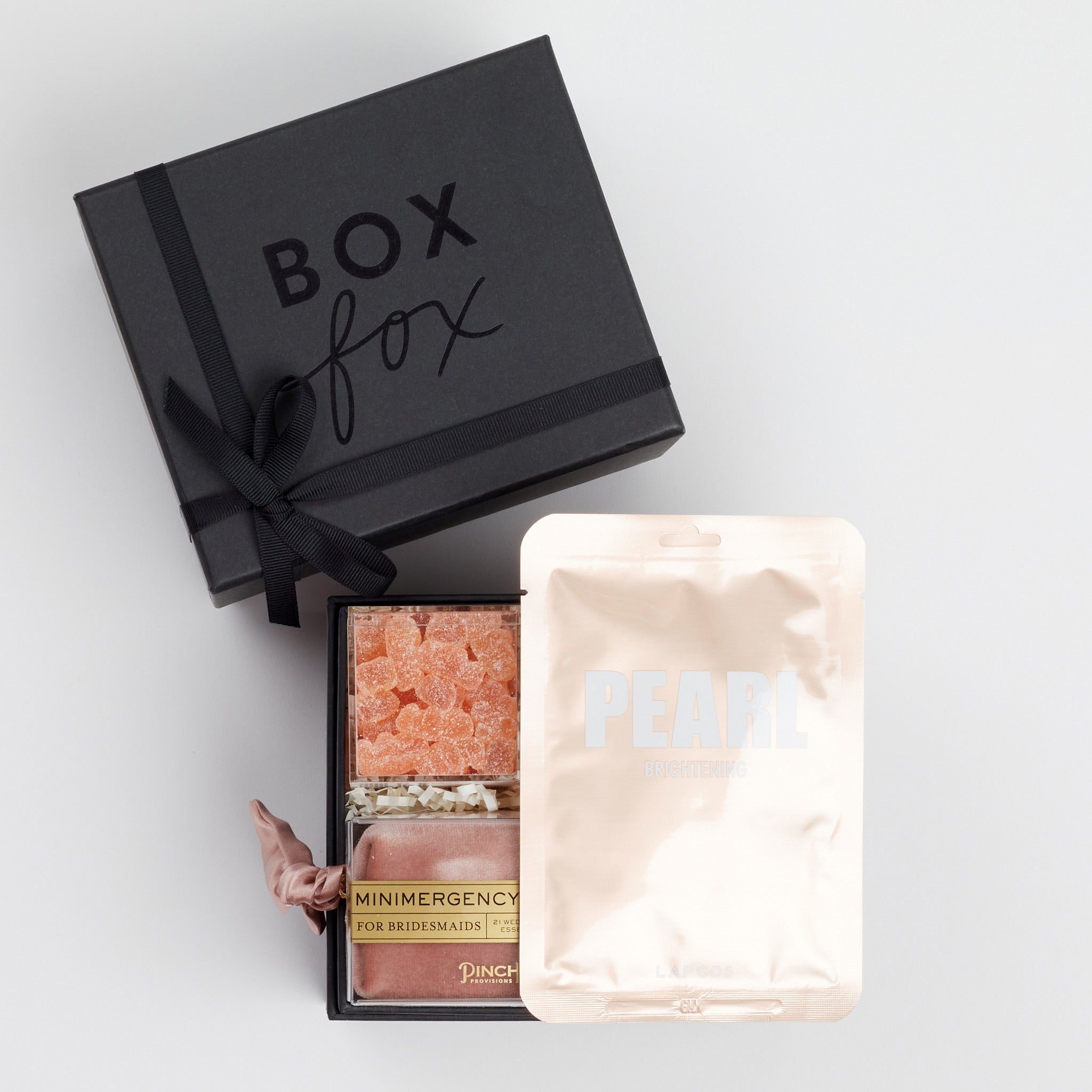 BOXFOX Bridesmaid Gift Box in Matte Black with Lapcos Pearl Brightening Mask, Sugarfina sparkling pink gummies, Pinch Provisions pinch velvet bridesmaids essential kit