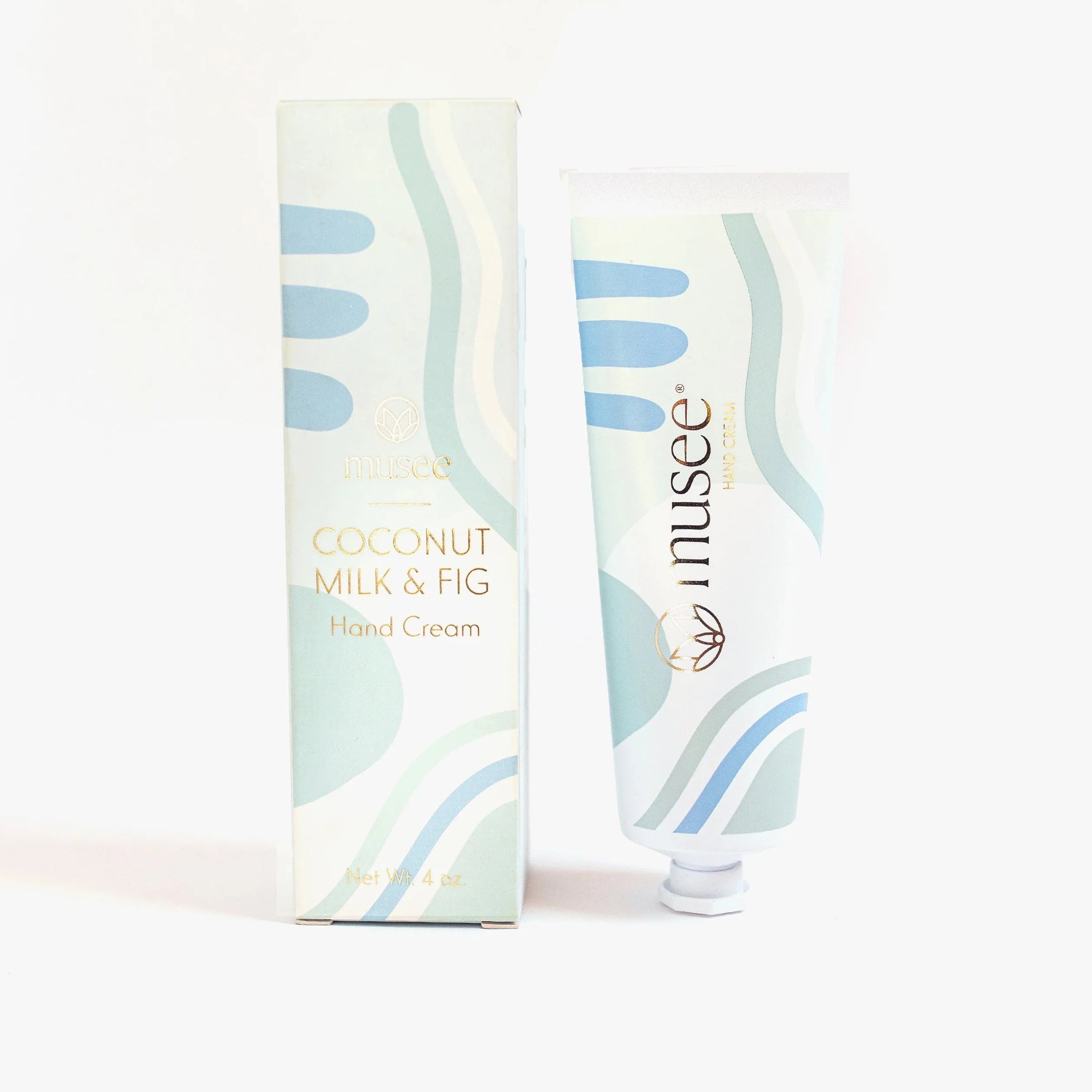 light green and blue abstract pattern on both the container and packaging of the coconut milk & fig hand cream. box is to the left of the tube for the hand cream