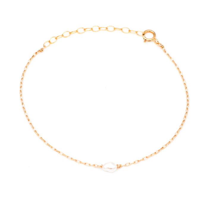 Dainty gold chain with small pearl in center.