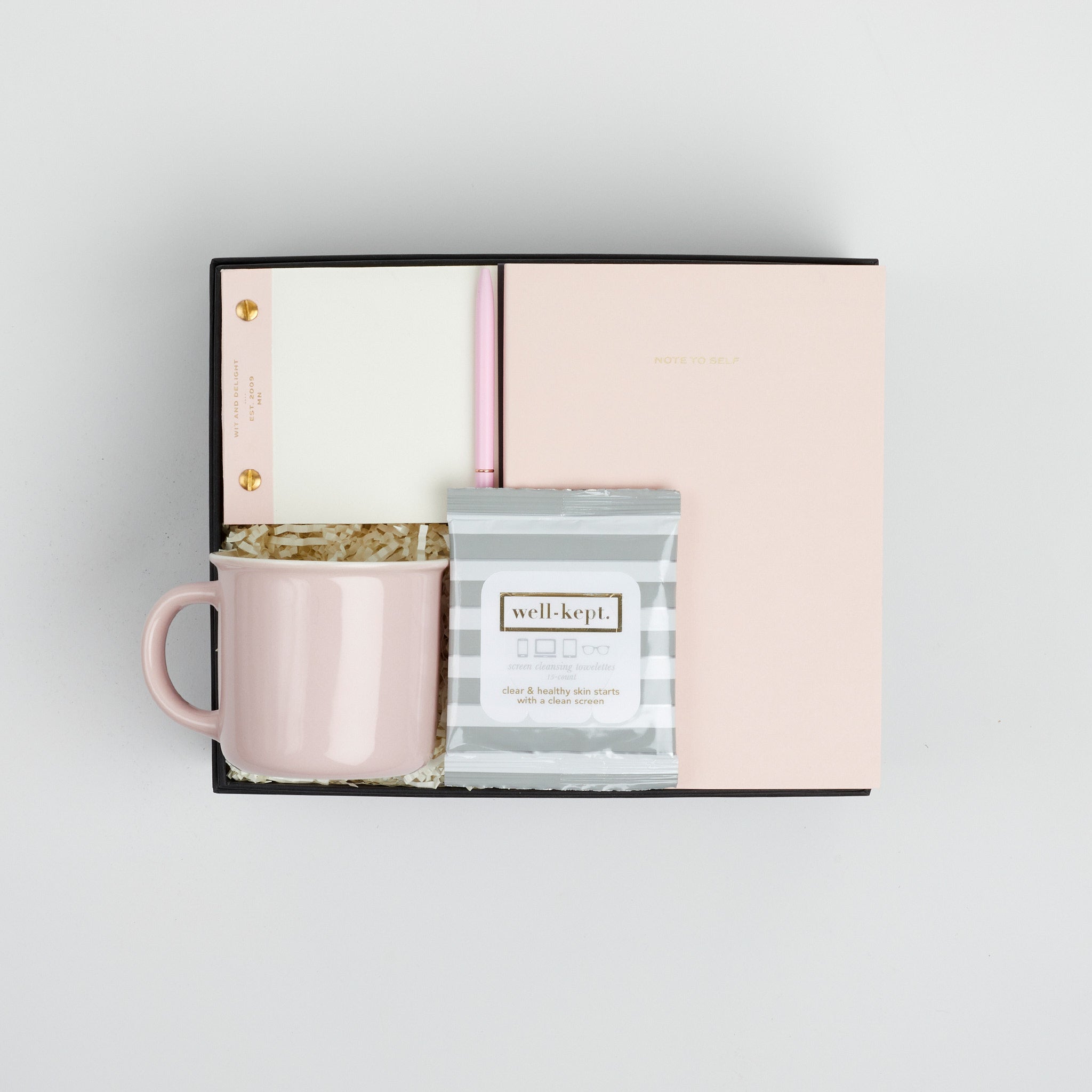 BOXFOX black Hustle Gift Box packed with Wit & Delight Pink Note to Self Journal, BOXFOX Pink Ceramic Mug, Well-Kept Hampton Tech Wipes, Sugarpaper Pink To Do Pad, and BOXFOX Pink Bullet Pen.