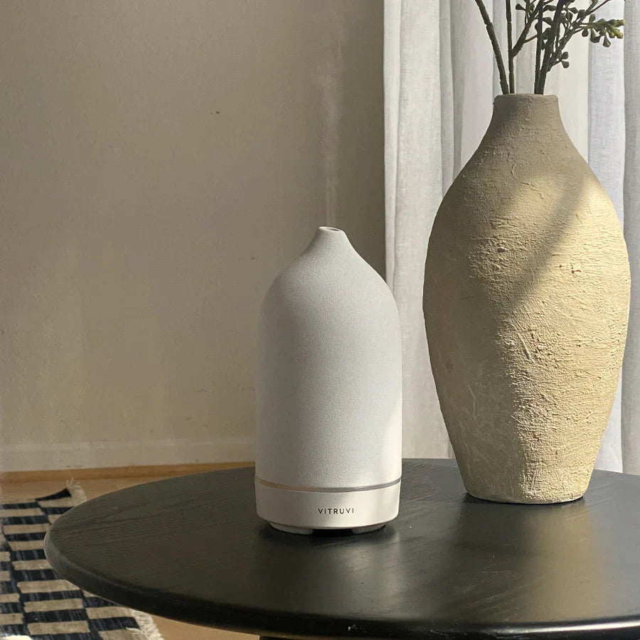 White Stone Essential Oil Diffuser on table next to vase
