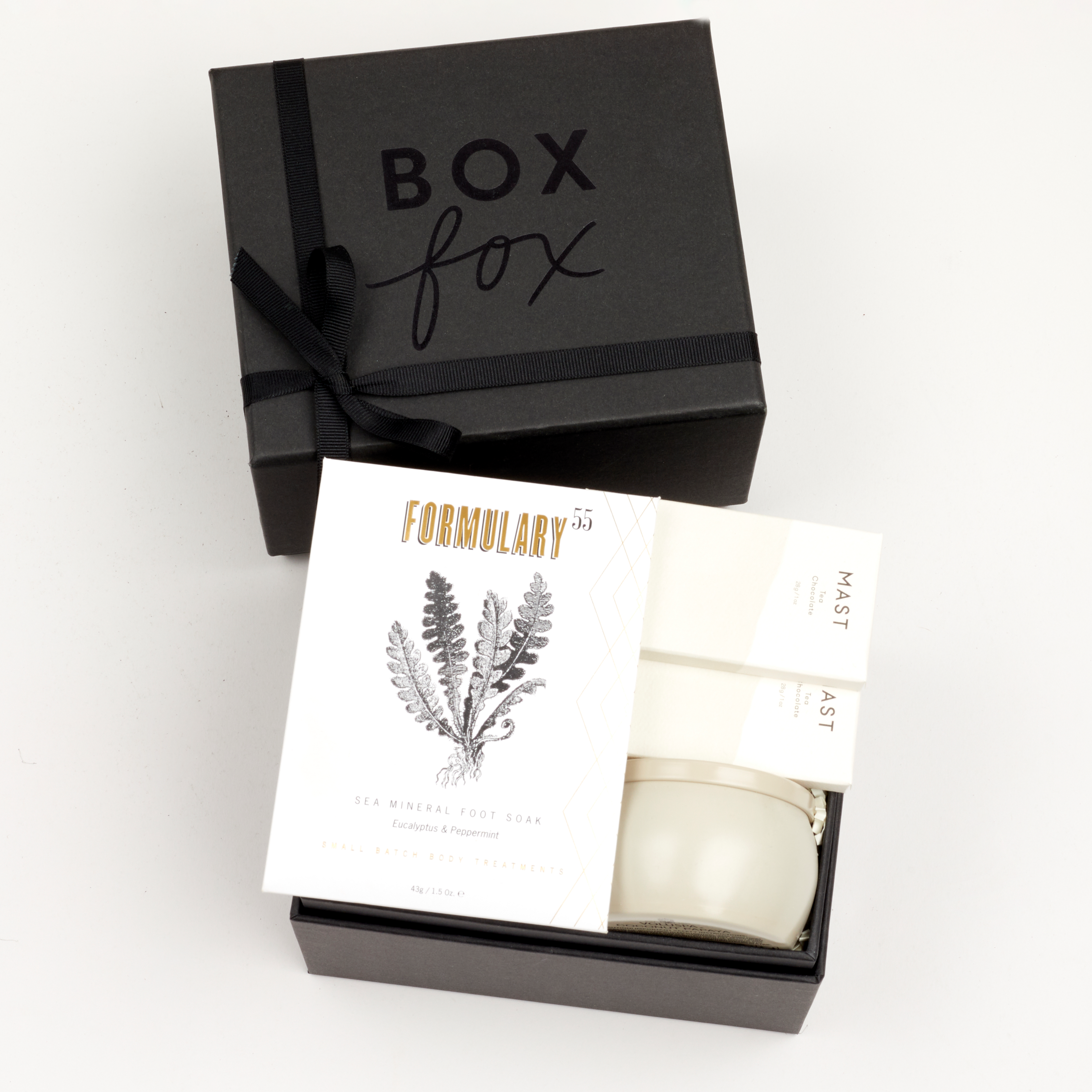 BOXFOX Black Gift Box filled with Voluspa Coconut Papaya Tin Candle, Formulary 55 Eucalyptus + Peppermint Foot Soak and Mast Brothers 2 Mini Tea Chocolate Bars