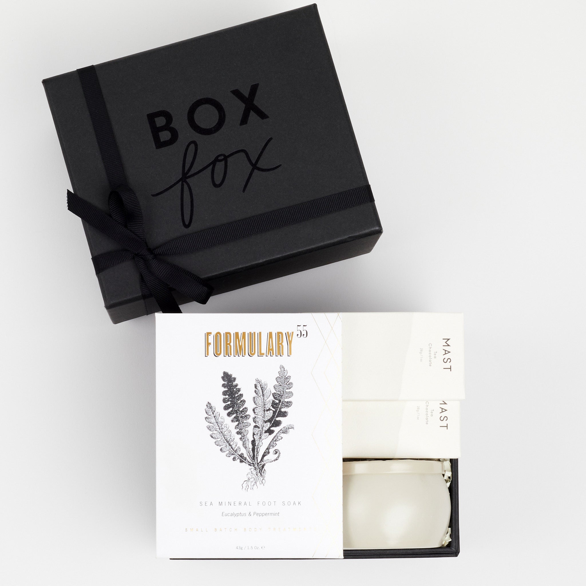 BOXFOX Black Gift Box filled with Voluspa Coconut Papaya Tin Candle, Formulary 55 Eucalyptus + Peppermint Foot Soak and Mast Brothers 2 Mini Tea Chocolate Bars