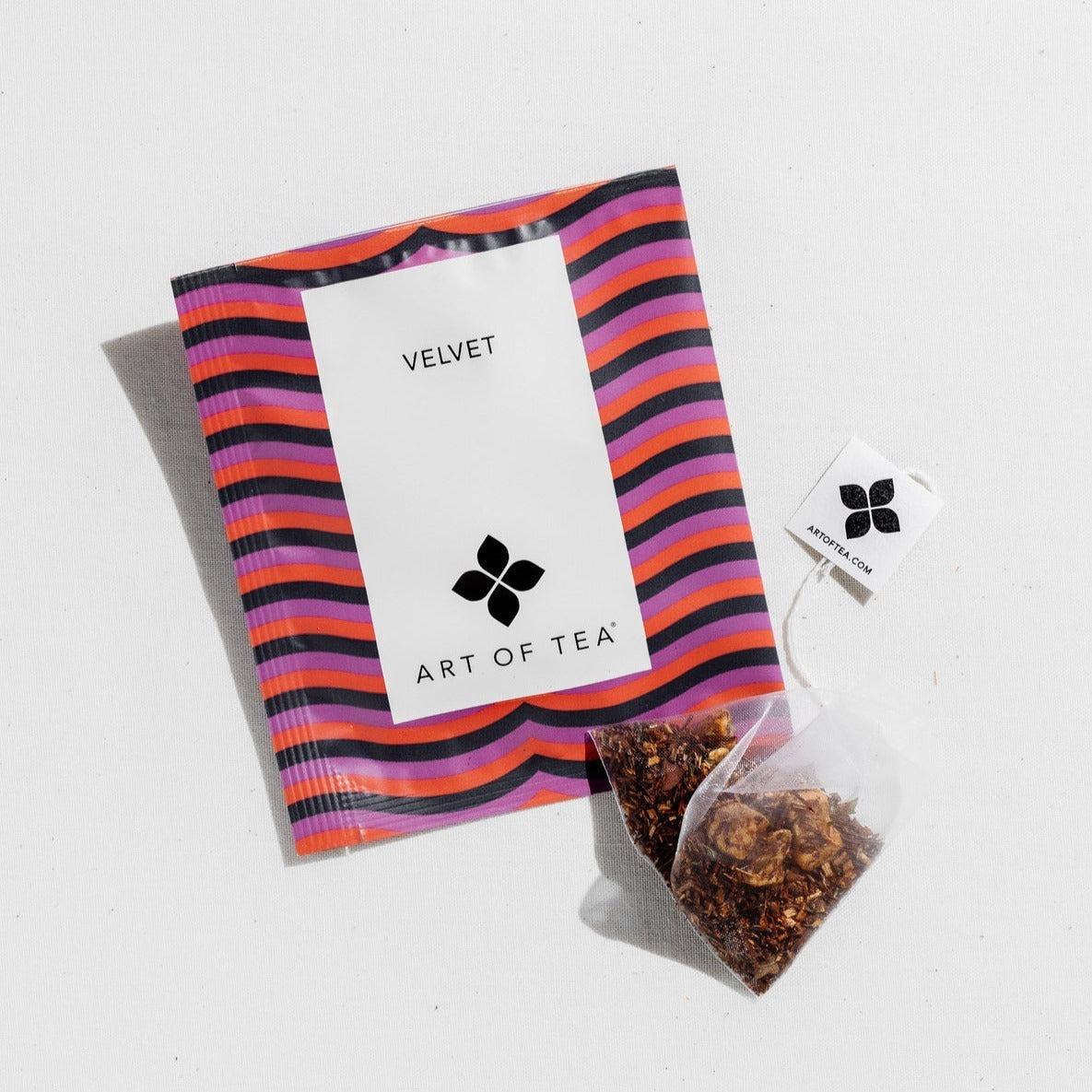 photo of the velvet tea sachet. the velvet tea sachet features black, purple, and red lines across the front of the packaging. it is laying on a white background. 